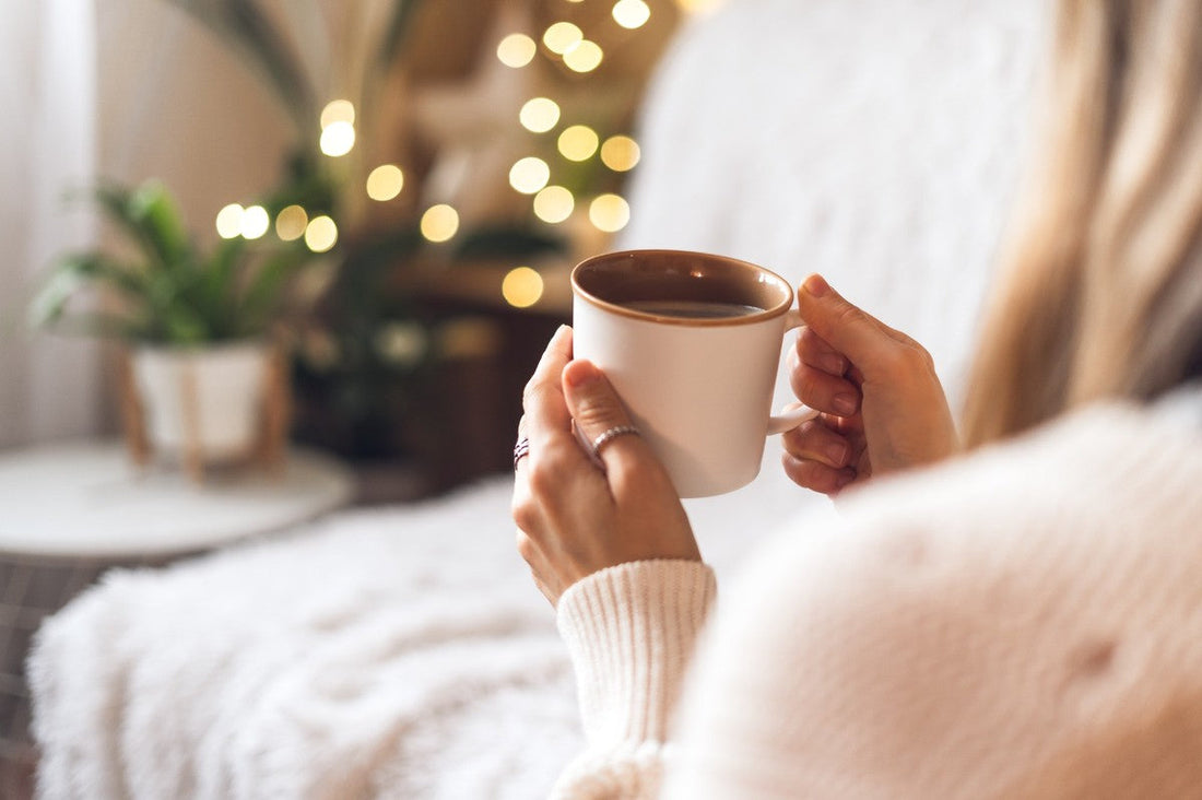 woman holding a cup of coffee and sitting on her couch